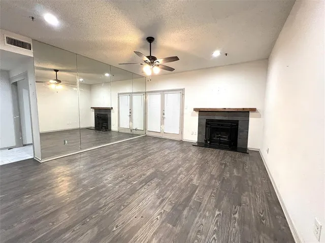 an empty room with wooden floor fireplace and ceiling fan