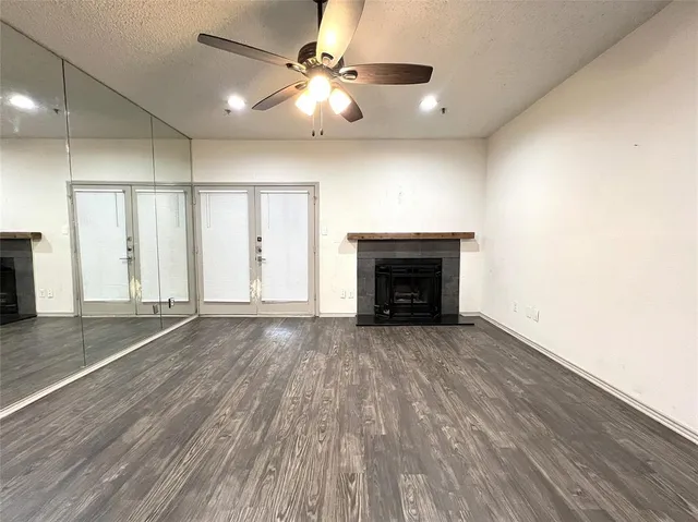 an empty room with wooden floor a ceiling fan and fireplace