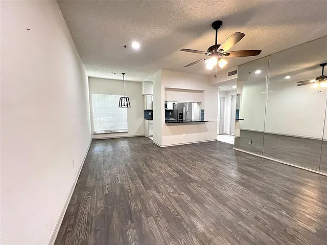 a view of a livingroom with wooden floor a ceiling fan and window