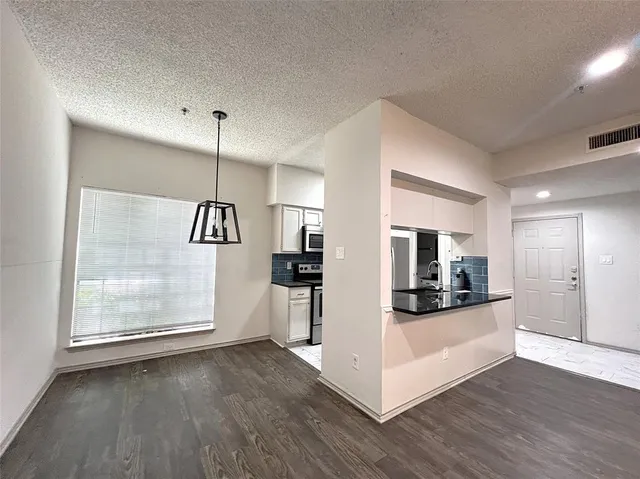 a view of a kitchen and an empty room with wooden floor kitchen view