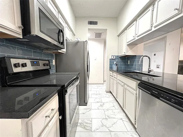 a kitchen with stainless steel appliances granite countertop a refrigerator a stove and a sink