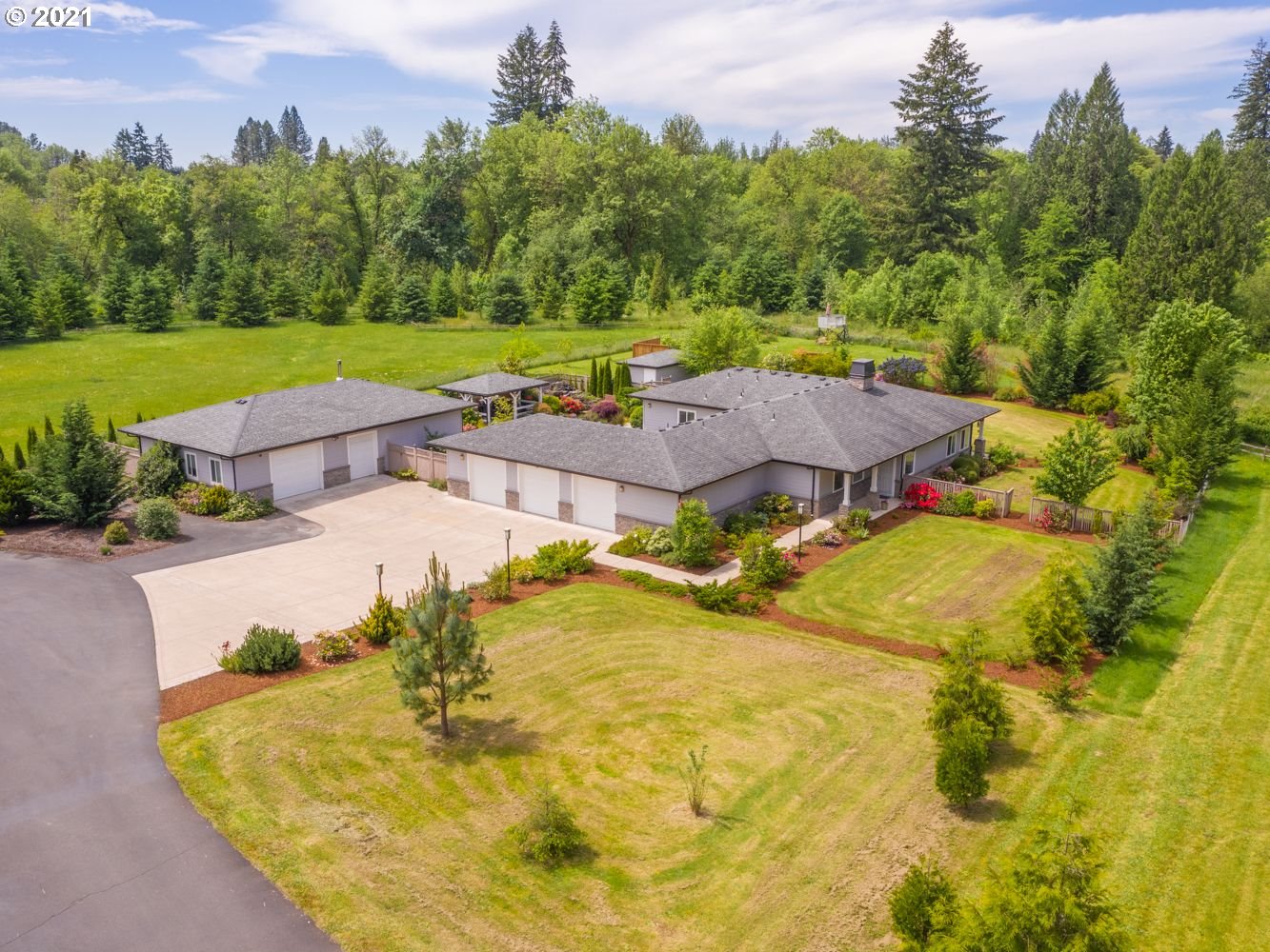 an aerial view of a house with swimming pool and large trees