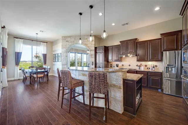 a kitchen with stainless steel appliances granite countertop wooden floors stove and white cabinets