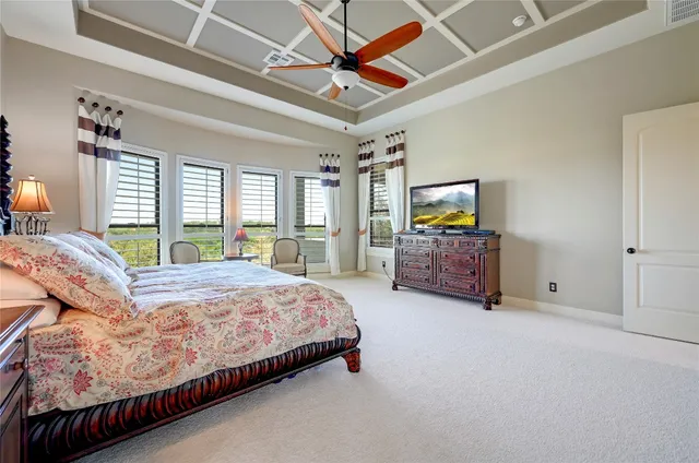 a spacious bedroom with a bed a dresser and a chandelier