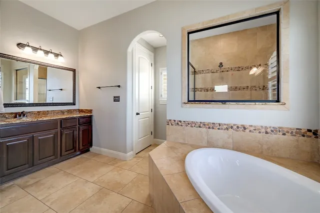 a spacious bathroom with a tub sink and mirror