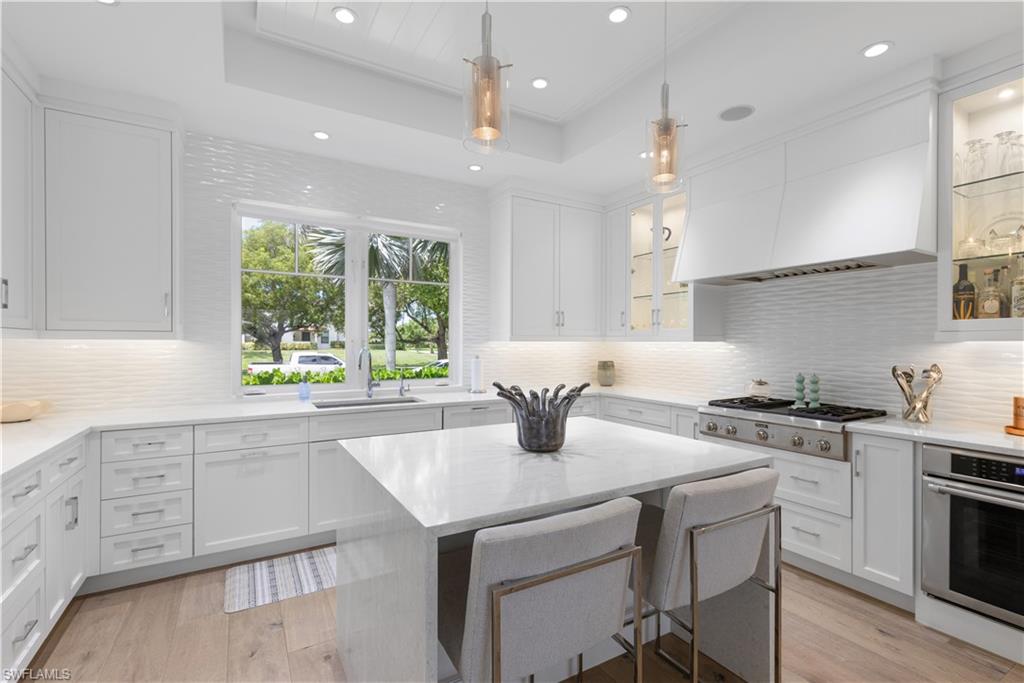1021 6th Street South Naples, FL 34102 - Photo 13 of 44 a kitchen with stainless steel appliances granite countertop a stove a sink dishwasher and a refrigerator with wooden floor