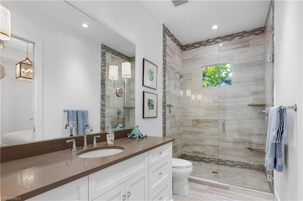 1021 6th Street South Naples, FL 34102 - Photo 20 of 44 a bathroom with a granite countertop sink a toilet a mirror and shower