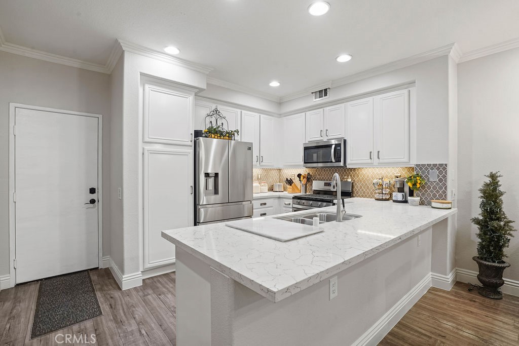 7701 Chambray Place, Unit 3 Rancho Cucamonga, CA 91739 - Photo 14 of 52 a kitchen that has a lot of white cabinets and stainless steel appliances