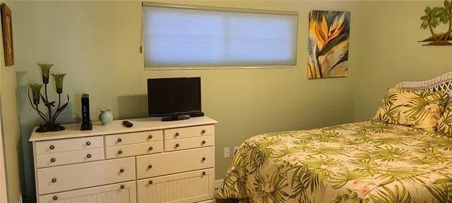 a bedroom with a bed and a flat tv screen on the dresser