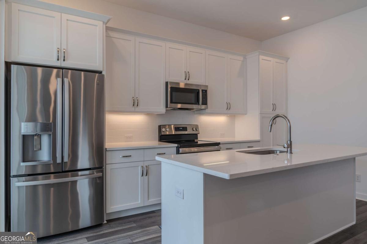 133 Devore Road, Unit 208 Alpharetta, GA 30009 - Photo 5 of 20 a kitchen with a refrigerator stove and white cabinets