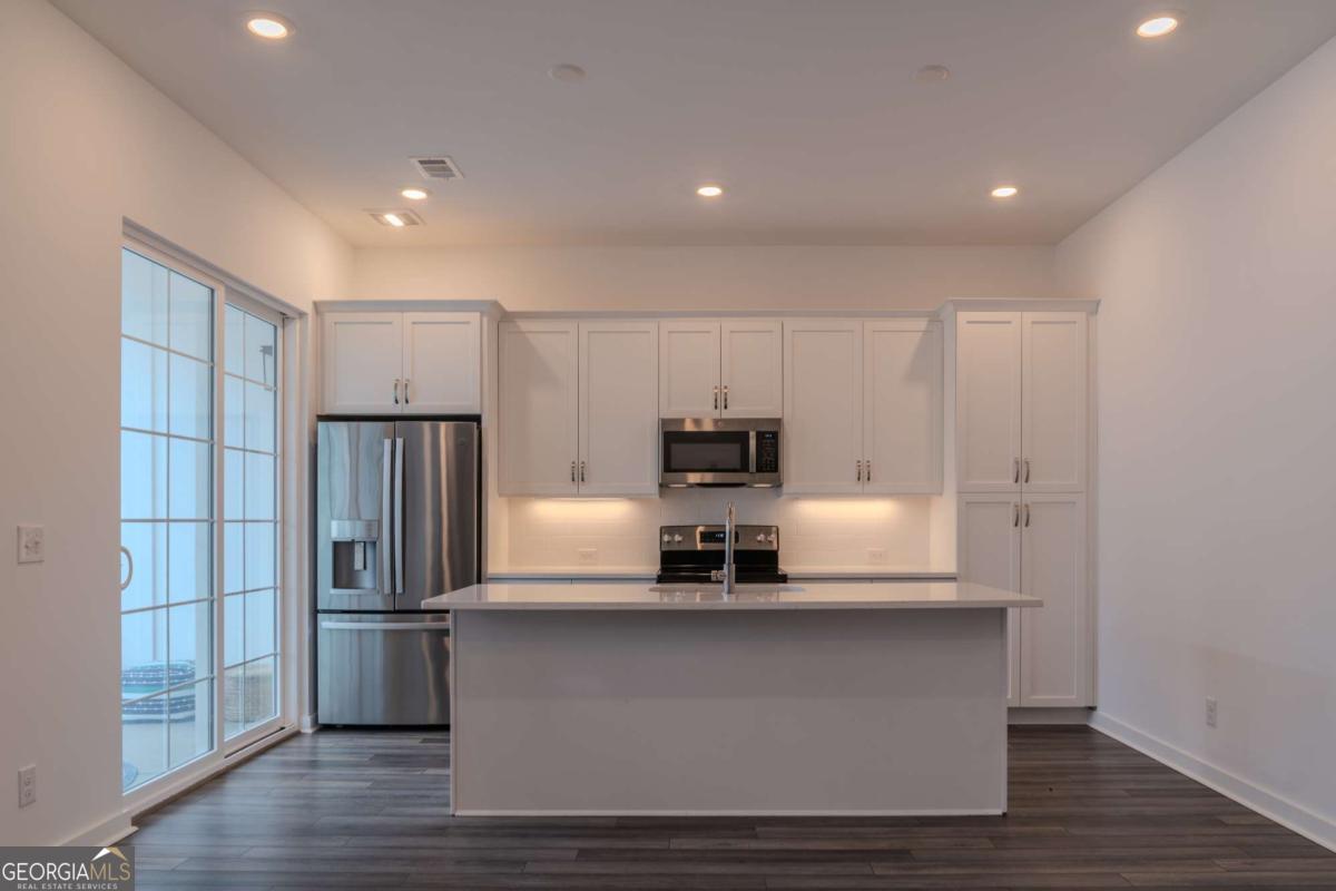 133 Devore Road, Unit 208 Alpharetta, GA 30009 - Photo 6 of 20 a large kitchen with stainless steel appliances a refrigerator and a stove top oven
