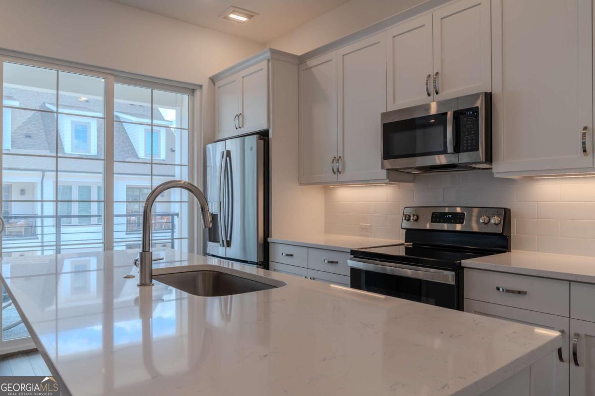 133 Devore Road, Unit 208 Alpharetta, GA 30009 - Photo 7 of 20 a kitchen with stainless steel appliances a stove microwave and sink