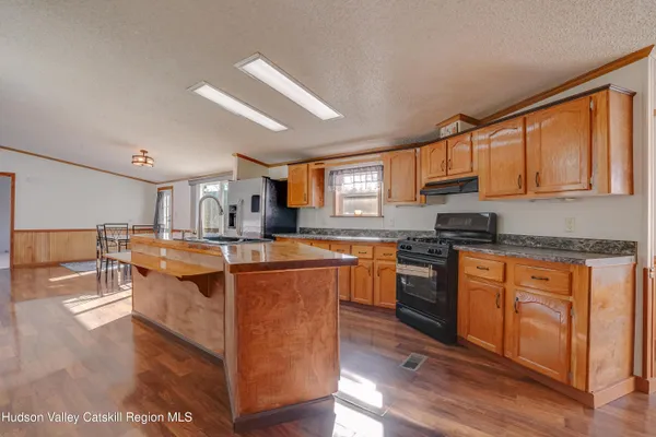 a kitchen with stainless steel appliances granite countertop a stove top oven a sink dishwasher a dining table and chairs with wooden floor