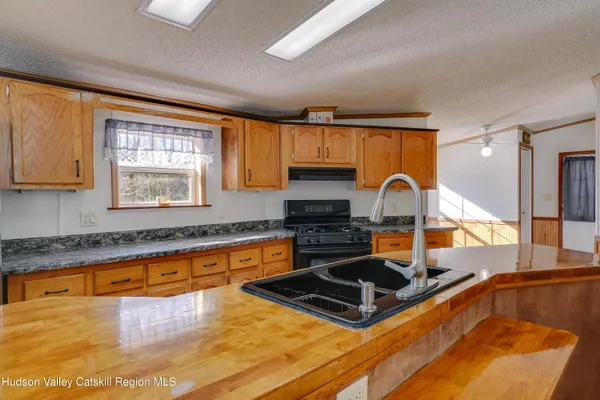 a kitchen with stainless steel appliances granite countertop a stove a sink and a granite counter tops with a large window