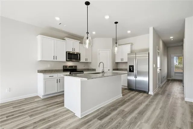 a kitchen with stainless steel appliances granite countertop a refrigerator a oven a sink and white cabinets