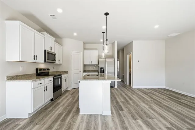 a large kitchen with cabinets wooden floor and stainless steel appliances