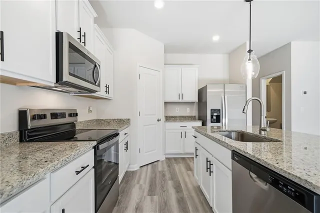 a kitchen with stainless steel appliances granite countertop a sink stove microwave and refrigerator