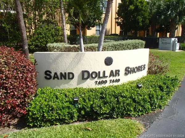 a view of a sign in a yard with potted plants and tree