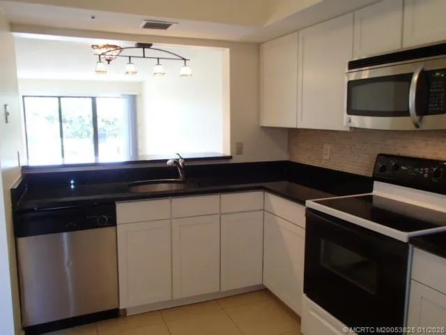 a kitchen with granite countertop white cabinets and black appliances