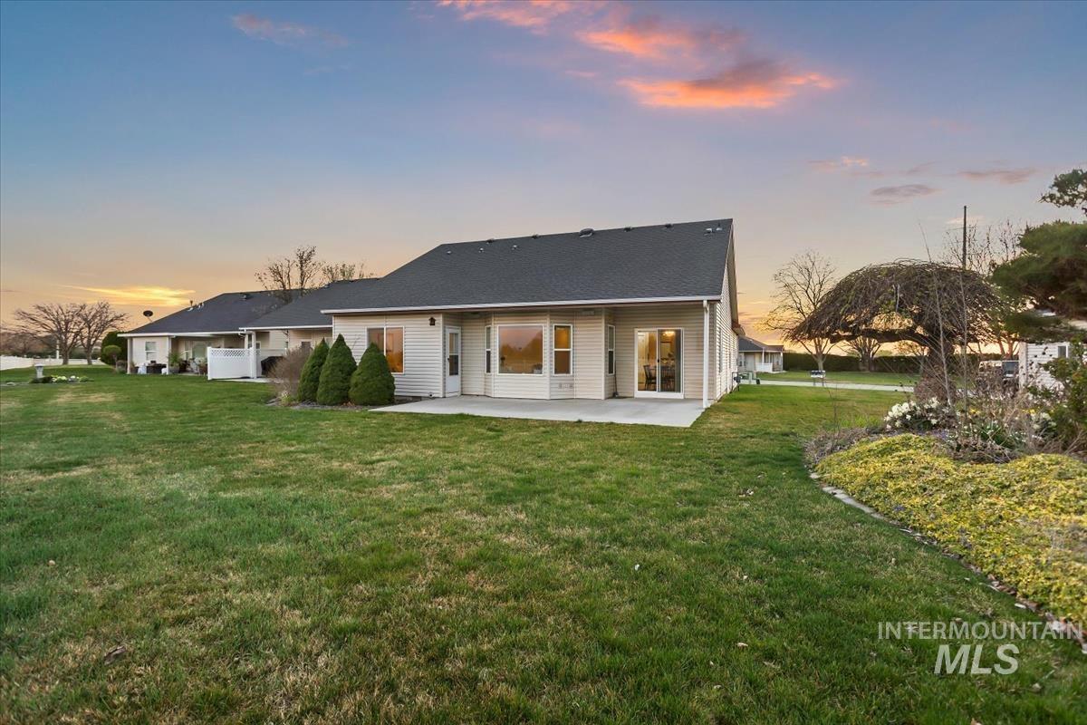 25074 The Driving Lane Caldwell, ID 83607 - Photo 28 of 32 Back of house at dusk featuring a yard and a patio area