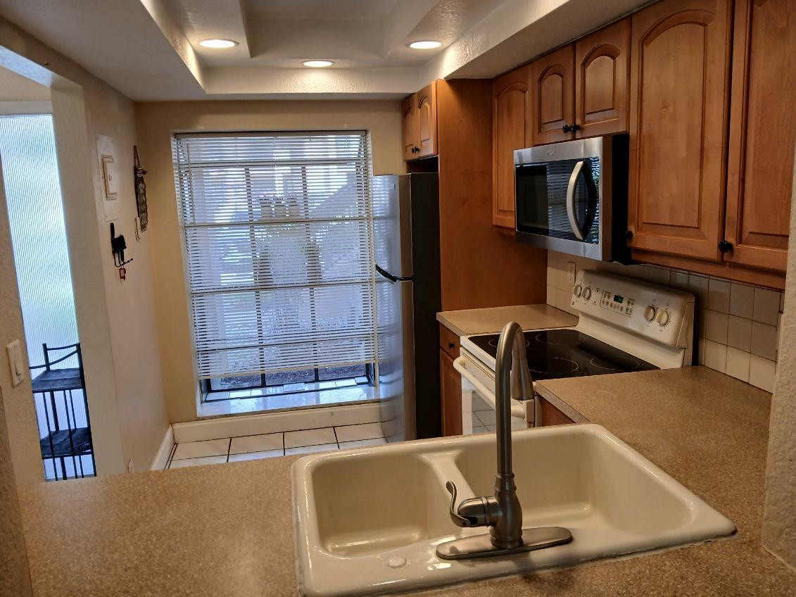 2339 Southwest 15th Street, Unit 19 Deerfield Beach, FL 33442 - Photo 5 of 15 a kitchen with stainless steel appliances granite countertop a refrigerator a stove and a sink with wooden cabinets