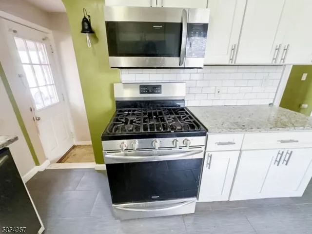 a kitchen with granite countertop a stove and a microwave