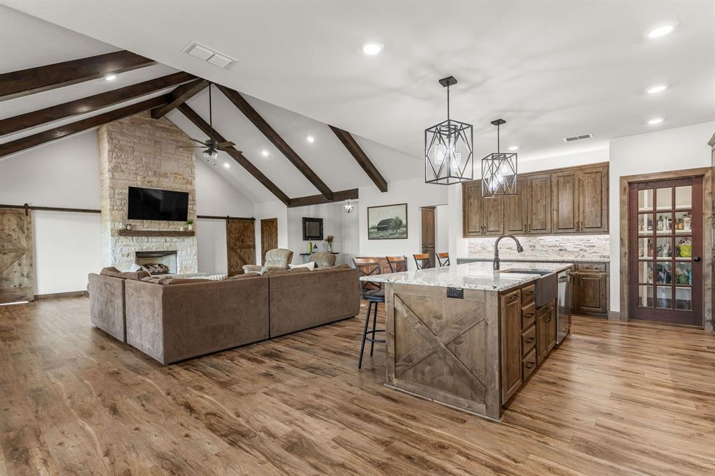 515 Sales Road Windthorst, TX 76389 - Photo 8 of 34 a living room with stainless steel appliances kitchen island granite countertop a table chairs in it and a wooden floor