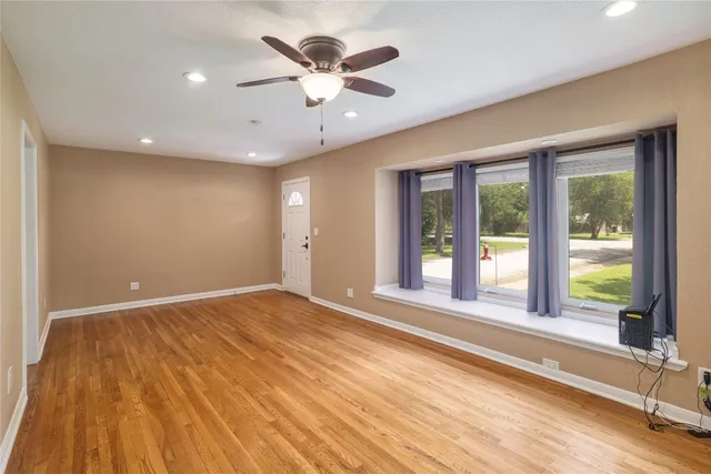 a view of an empty room with a window and wooden floor
