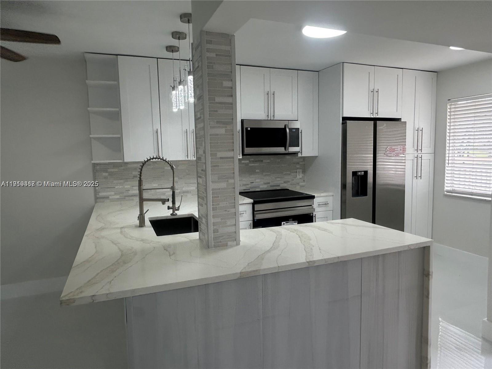 6935 Huntington Lane, Unit 107 Delray Beach, FL 33446 - Photo 5 of 23 a kitchen with stainless steel appliances a refrigerator sink and microwave