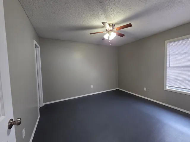 an empty room with windows and fan