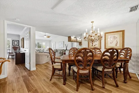 a dining room with furniture a chandelier and wooden floor