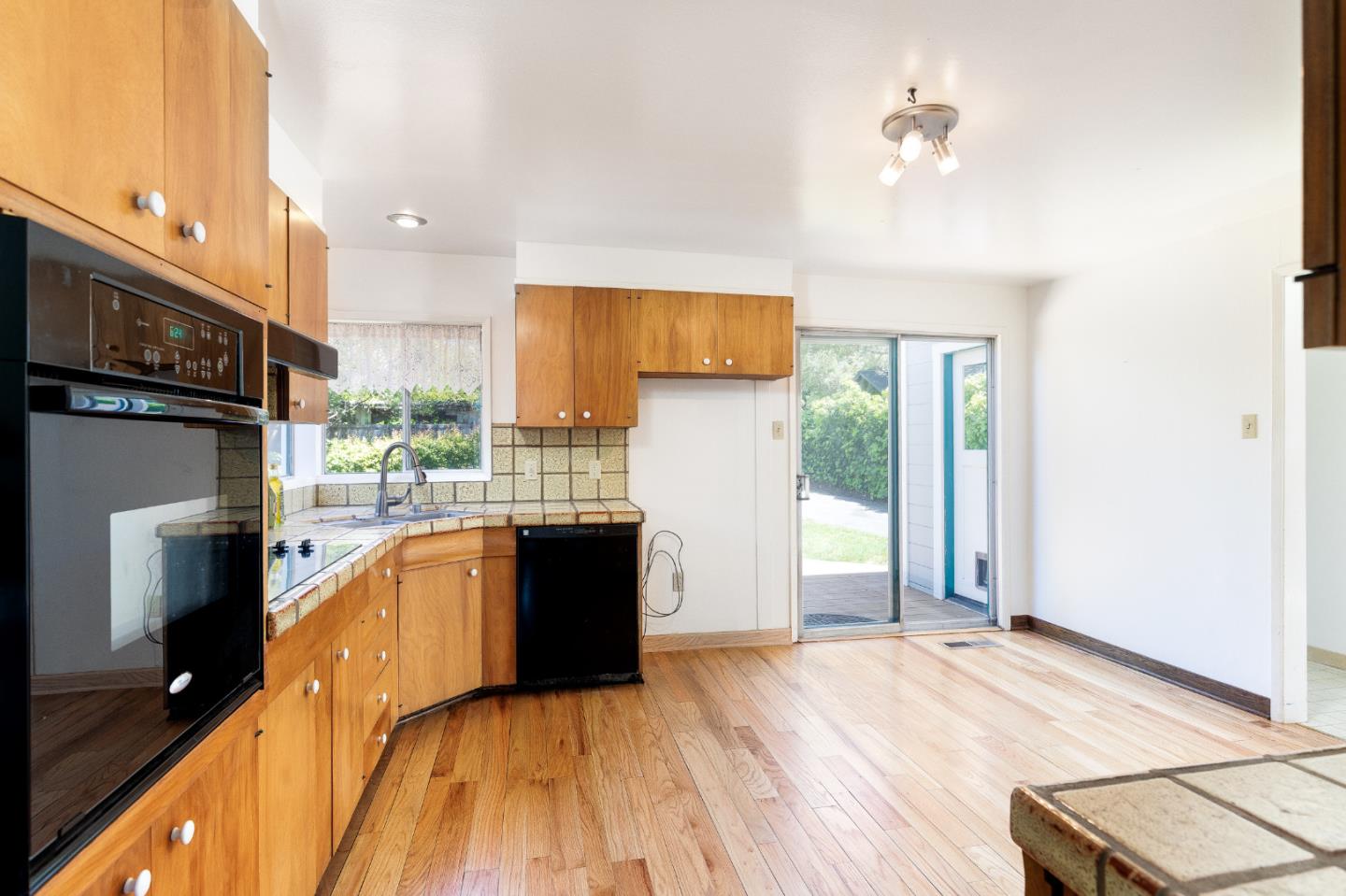 106 Cliff Avenue Capitola, CA 95010 - Photo 20 of 30 a kitchen with stainless steel appliances granite countertop a refrigerator a stove top oven and a sink with wooden floor