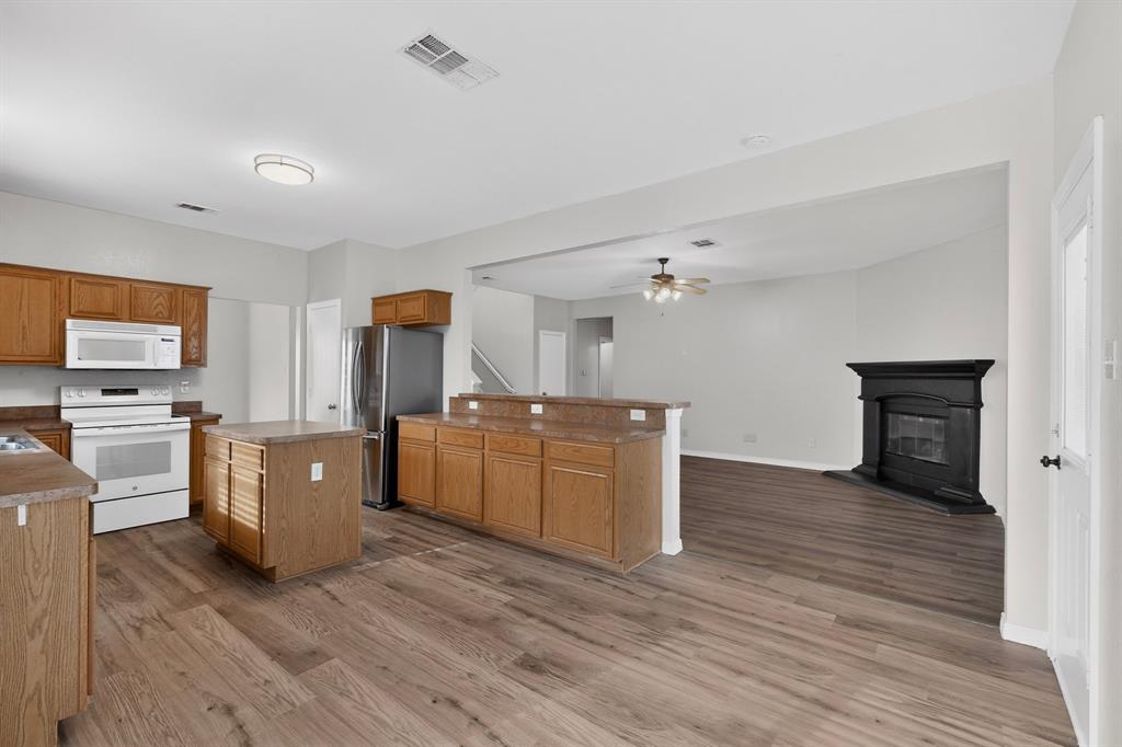 3401 Newgate Street Midlothian, TX 76065 - Photo 11 of 34 Open-concept kitchen featuring wood-finish flooring, wood cabinetry, stainless steel refrigerator, white range, and a central island