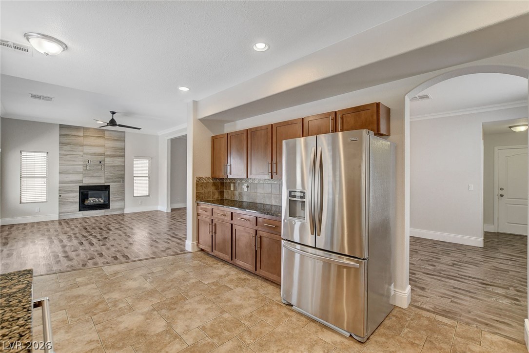 191 Verde Ridge Court Henderson, NV 89012 - Photo 15 of 36 Kitchen with stainless steel refrigerator with ice dispenser, a ceiling fan, baseboards, ornamental molding, and brown cabinets