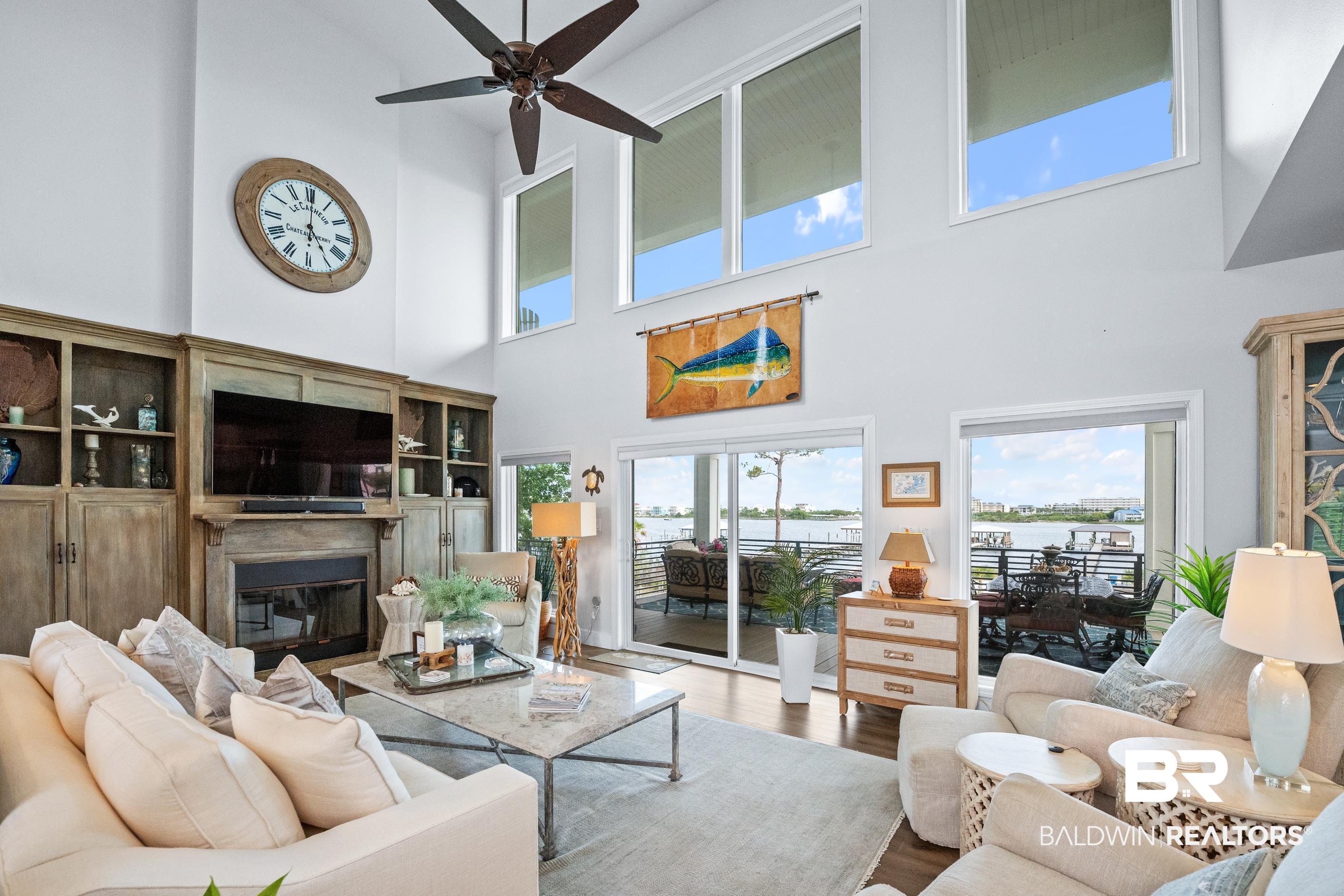 30954 River Road Orange Beach, AL 36561 - Photo 12 of 59 Living area with a high ceiling, a ceiling fan, wood finished floors, a glass covered fireplace, and plenty of natural light