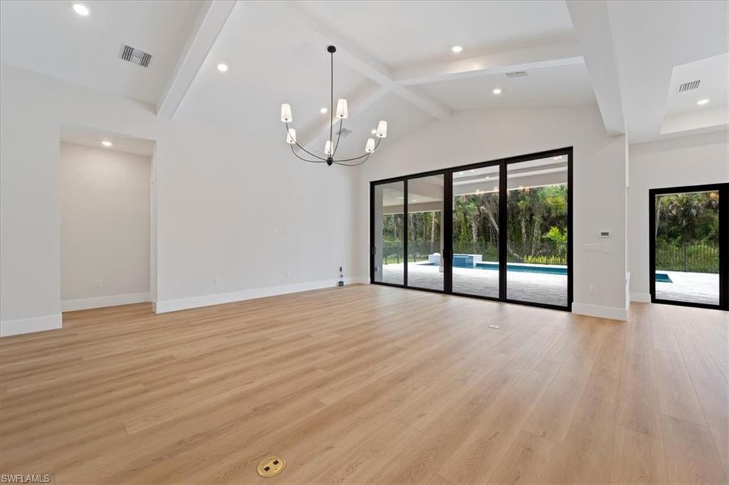 699 1st Street Northwest Naples, FL 34120 - Photo 11 of 42 an empty room with wooden floor and large windows