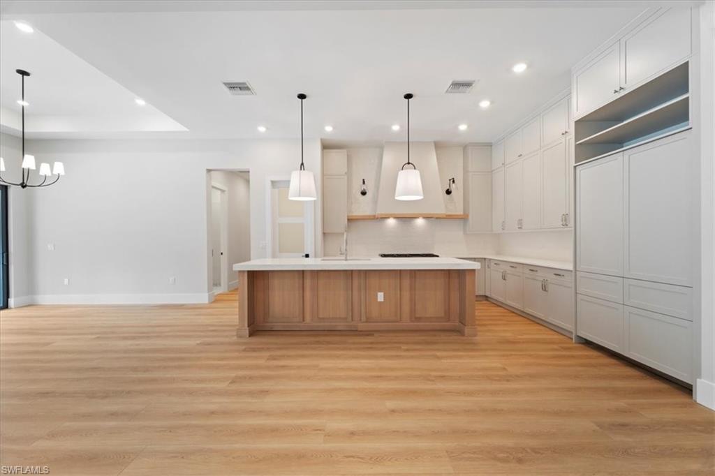 699 1st Street Northwest Naples, FL 34120 - Photo 13 of 42 a large kitchen with kitchen island white cabinets and stainless steel appliances