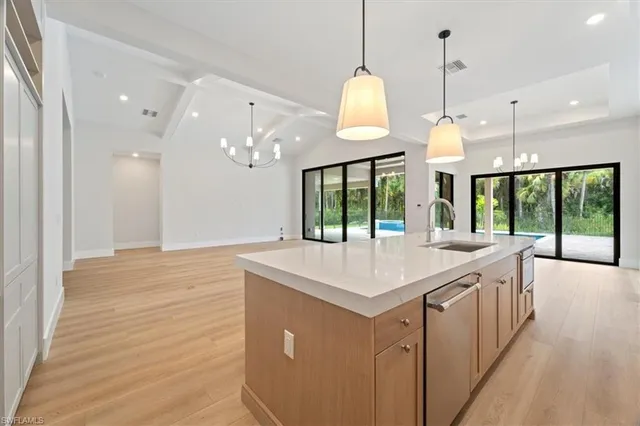 a kitchen with a stove a sink a large window and wooden floor