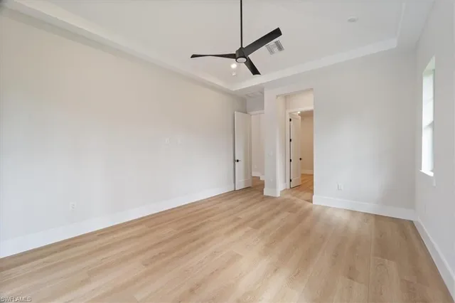 a view of empty room with wooden floor and fan