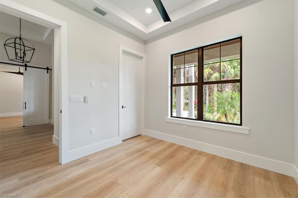 699 1st Street Northwest Naples, FL 34120 - Photo 23 of 42 an empty room with wooden floor and windows