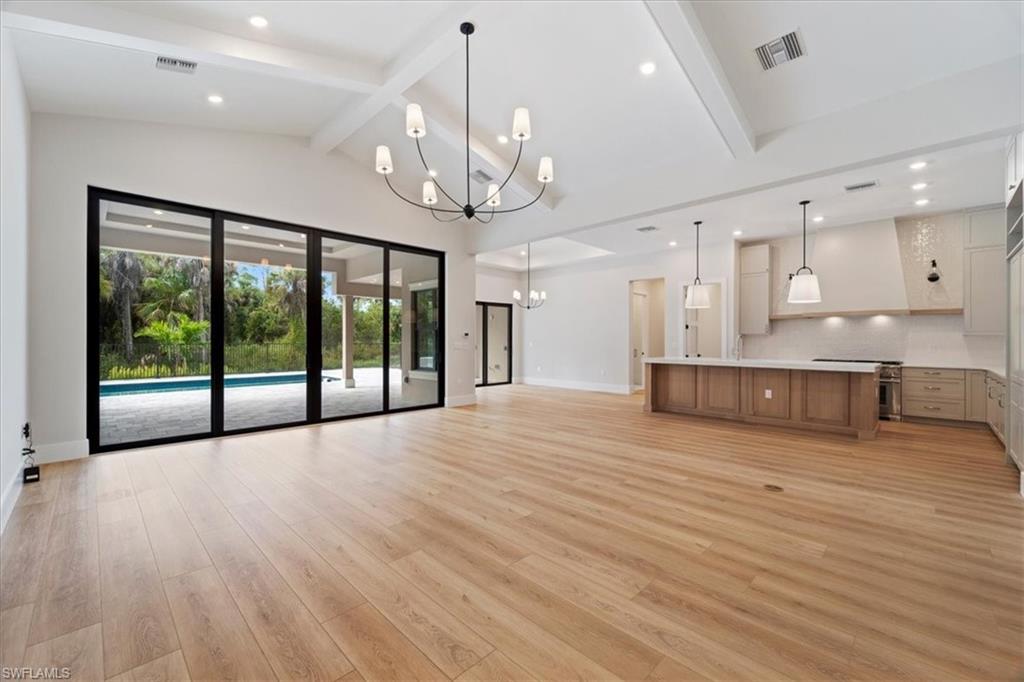 699 1st Street Northwest Naples, FL 34120 - Photo 10 of 42 a view of an empty room with wooden floor and a kitchen