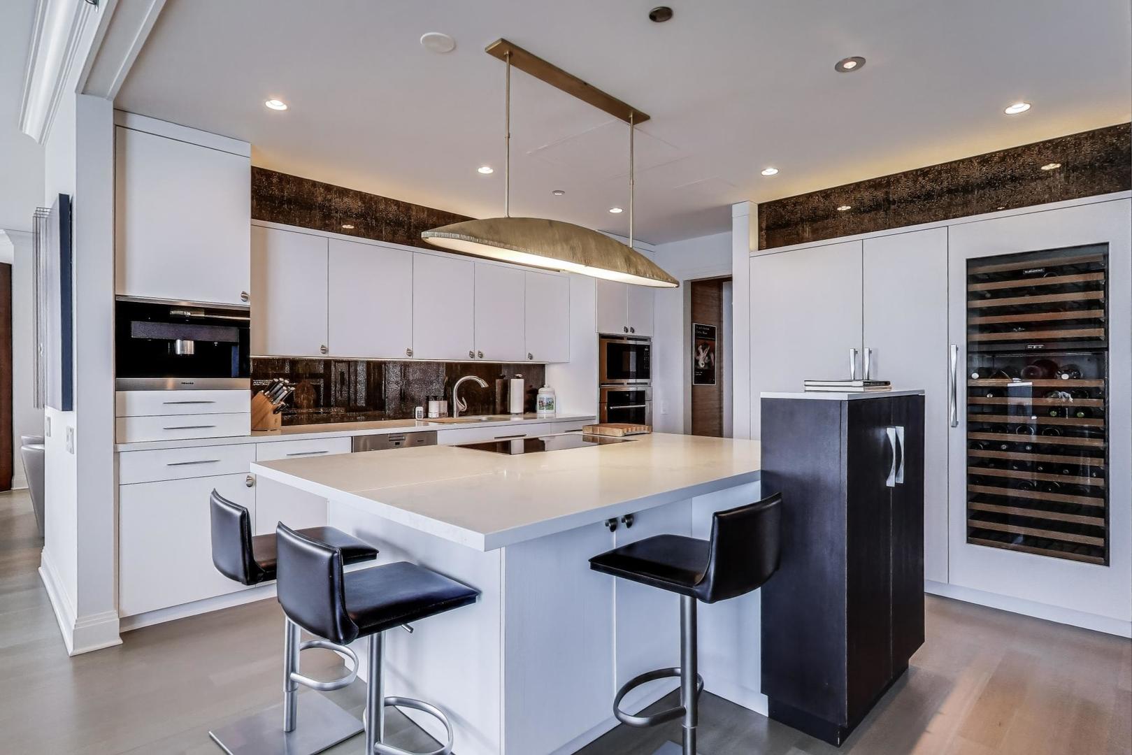 840 North Lake Shore Drive, Unit 2401 Chicago, IL 60611 - Photo 16 of 40 a kitchen with stainless steel appliances kitchen island granite countertop a refrigerator a sink and wooden cabinets