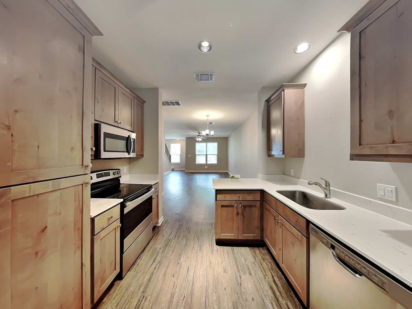 179 Holly Street, Unit 503 Georgetown, TX 78626 - Photo 4 of 18 a kitchen with granite countertop a sink wooden floor and stainless steel appliances