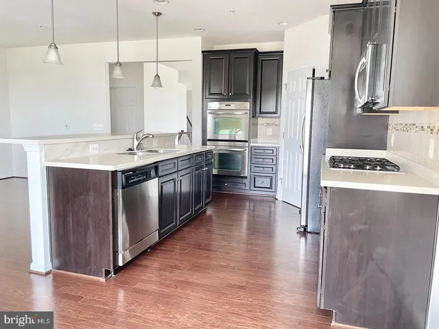 a kitchen with stainless steel appliances granite countertop a refrigerator a sink dishwasher a stove and a refrigerator with wooden floor