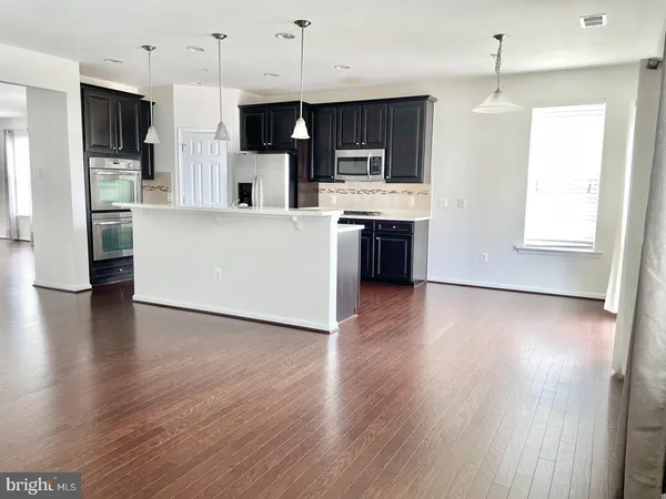 a large kitchen with stainless steel appliances wooden floors and white cabinets