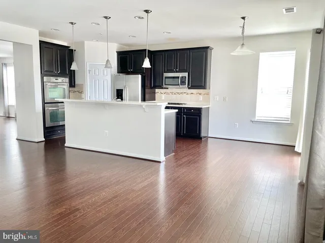 a large kitchen with stainless steel appliances wooden floors and white cabinets