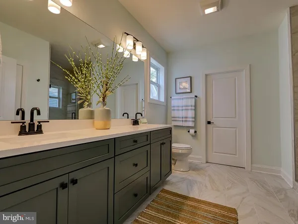 a spacious bathroom with a double vanity sink a toilet and a mirror