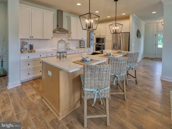 a kitchen with stainless steel appliances kitchen island granite countertop a sink a stove and a dining table with wooden floor