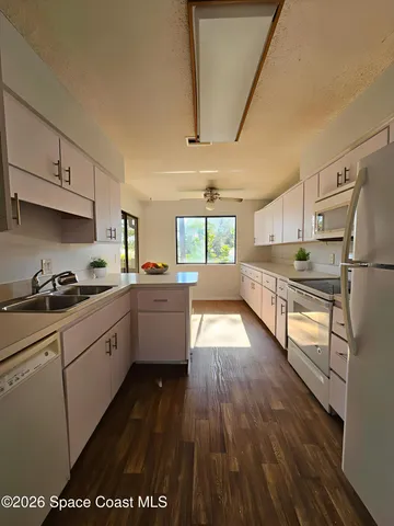 a kitchen with stainless steel appliances a refrigerator a sink dishwasher a stove and white countertops with wooden floor