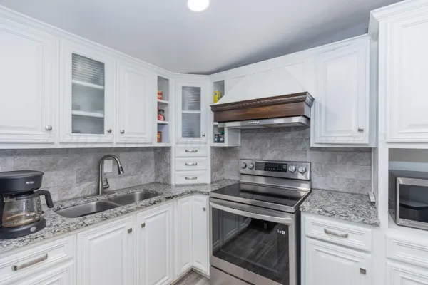 a kitchen with granite countertop a sink stove and cabinets